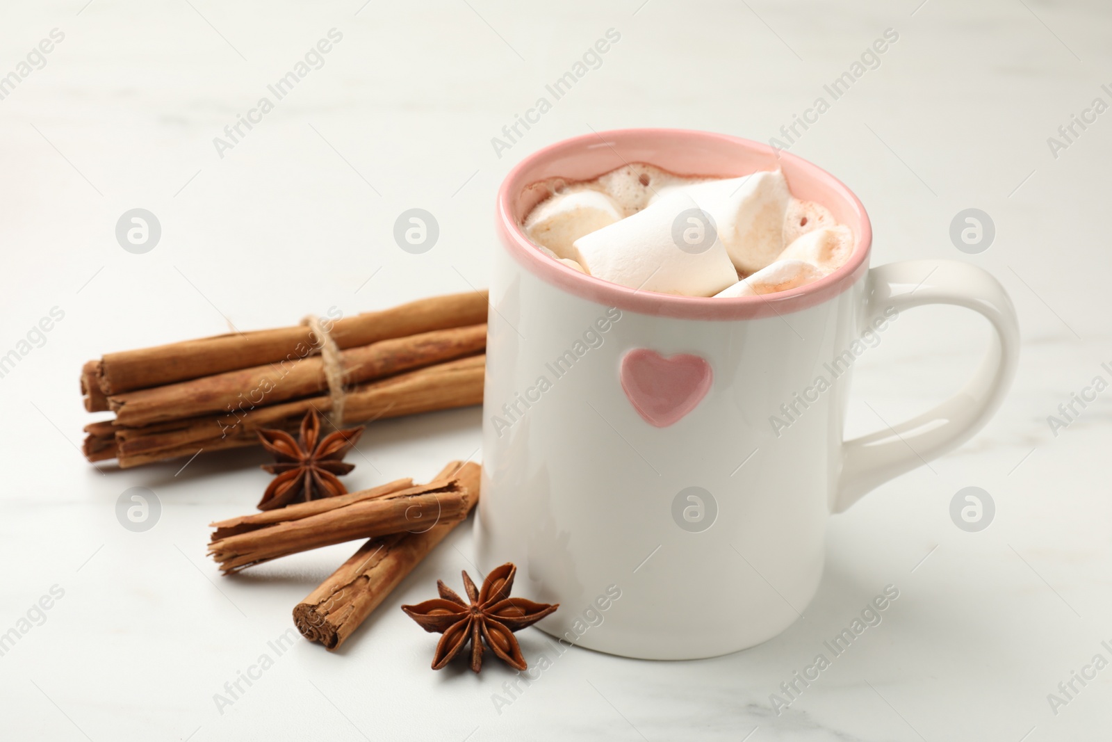 Photo of Tasty hot chocolate with marshmallows and spices on white marble table, closeup