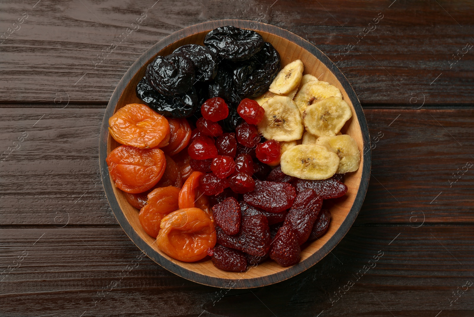 Photo of Mix of delicious dried fruits on wooden table, top view