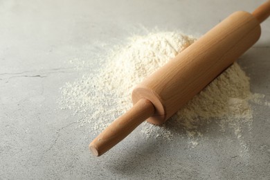 Photo of Flour and rolling pin on grey table, closeup. Space for text