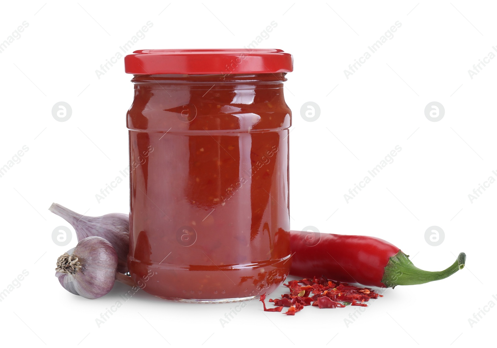 Photo of Spicy chili sauce in glass jar, garlic and pepper isolated on white