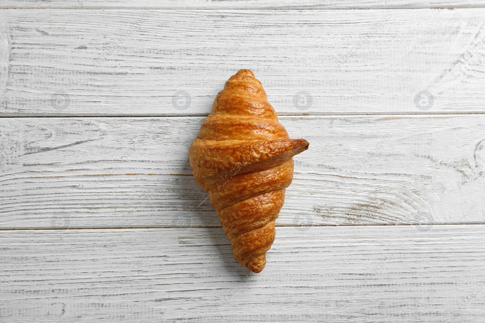 Photo of Tasty croissant on white wooden background, top view. French pastry