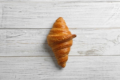 Photo of Tasty croissant on white wooden background, top view. French pastry