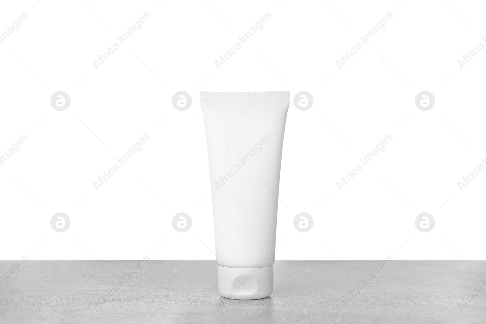 Photo of Tube of hand cream on gray table against white background