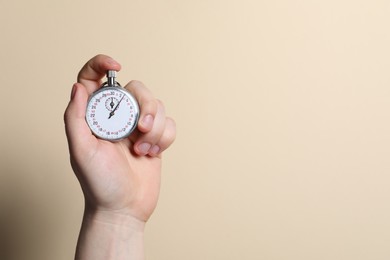 Man holding vintage timer on beige background, closeup. Space for text