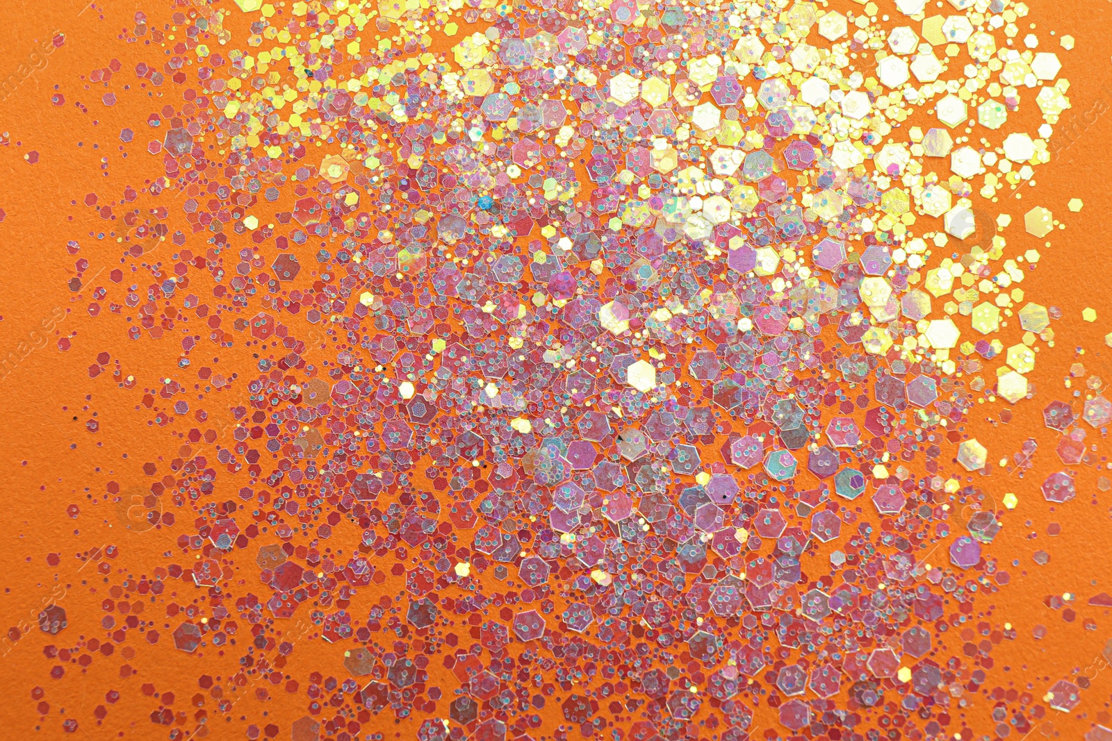 Photo of Shiny bright lilac glitter on orange background, flat lay