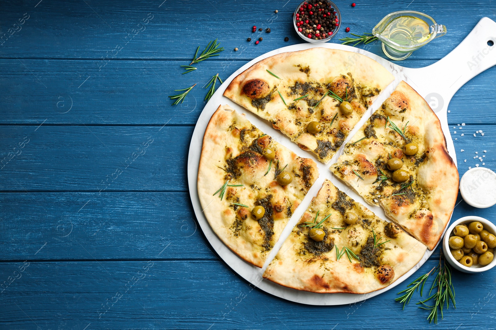 Photo of Delicious focaccia bread with green olives on blue wooden table, flat lay. Space for text