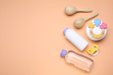 Photo of Flat lay composition with baby care products and accessories on pale orange background, space for text