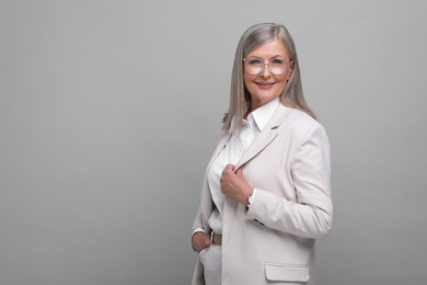 Photo of Portrait of beautiful senior woman in glasses on grey background. Space for text