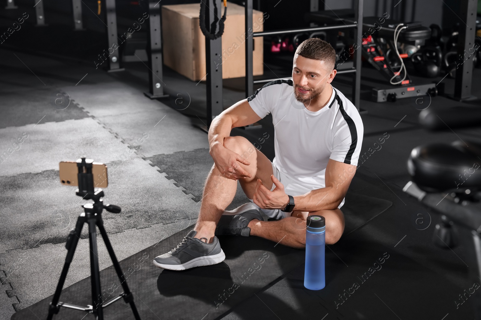 Photo of Trainer streaming online workout with phone at gym