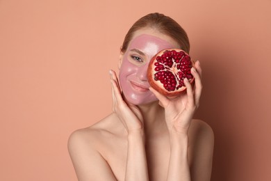 Young woman with pomegranate face mask and fresh fruit on pale coral background