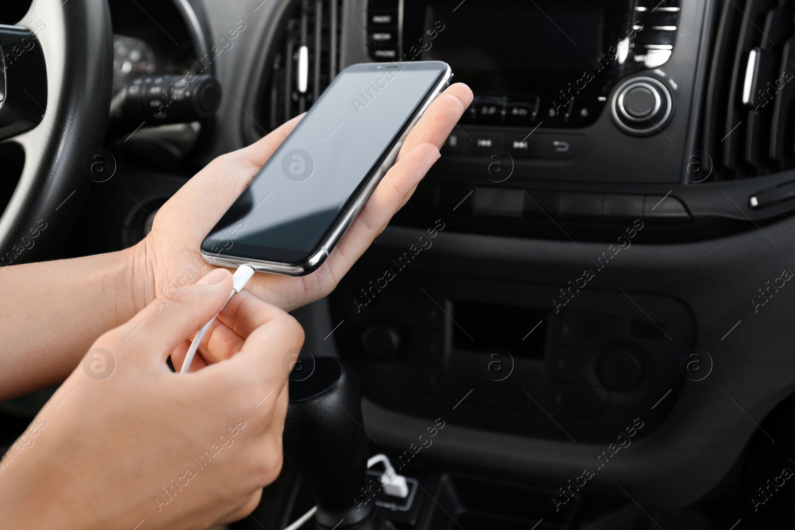 Photo of Person charging phone with USB cable in car