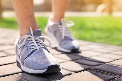 Image of Sporty young man in training shoes outdoors on sunny day, closeup