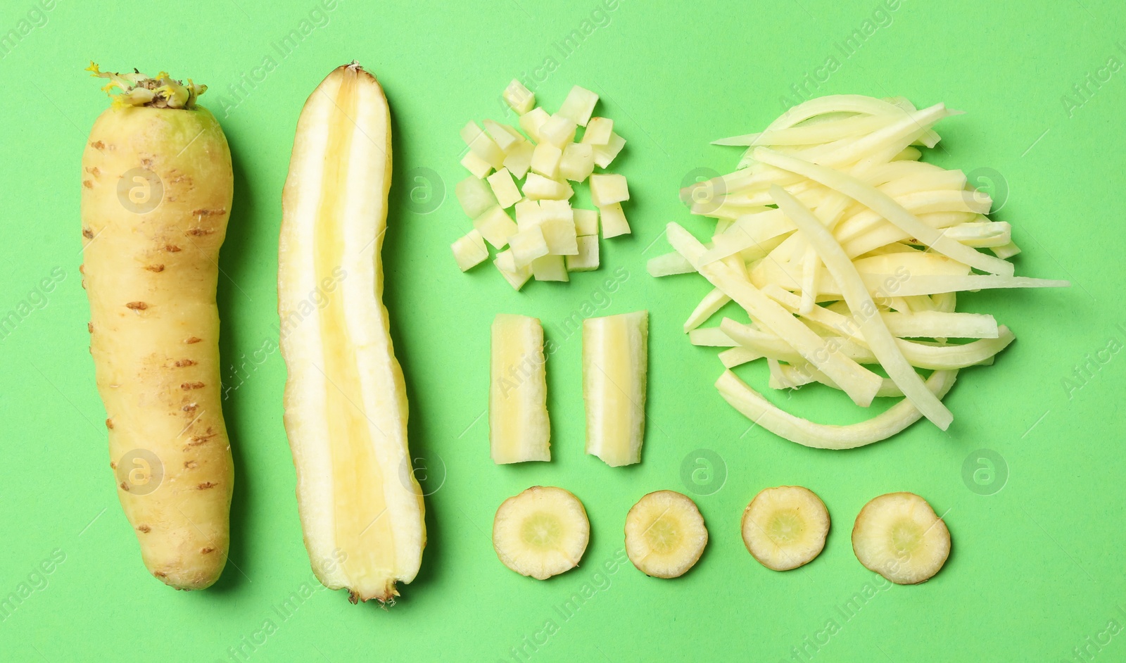 Photo of Whole and cut raw white carrots on green background, flat lay