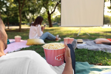 Photo of Young man with popcorn watching movie in open air cinema, closeup. Space for text