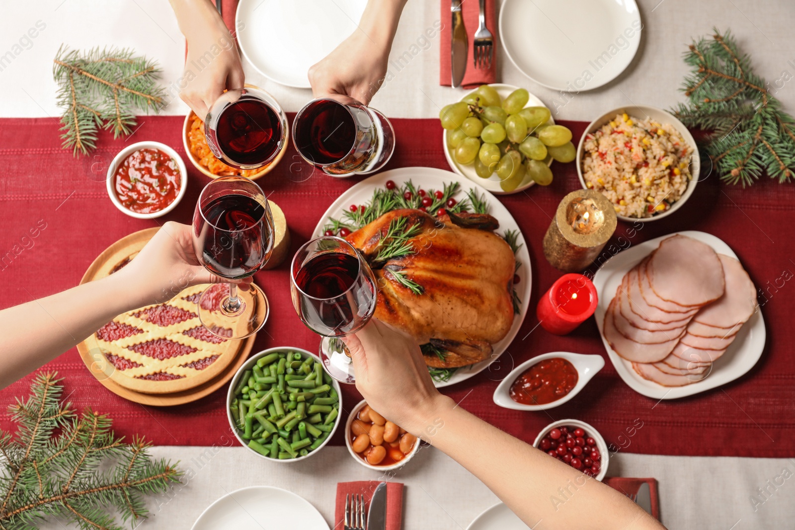 Photo of Women clinking glasses of wine over festive table with delicious roasted turkey, top view