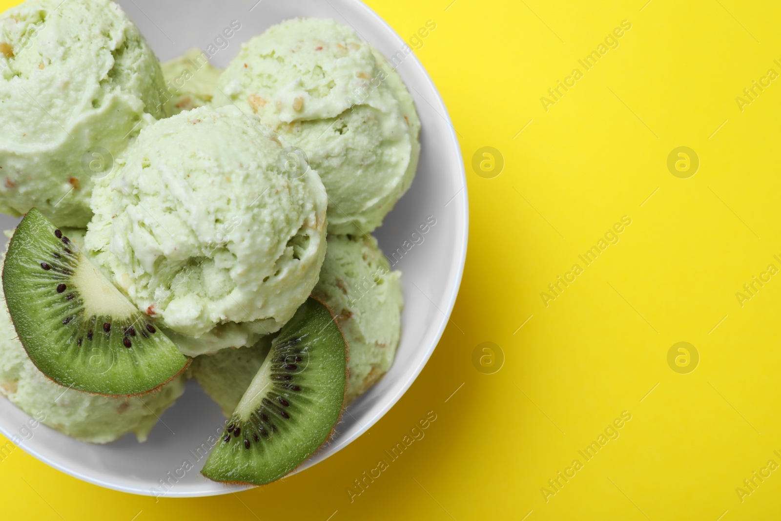 Photo of Delicious kiwi ice cream on yellow background, top view