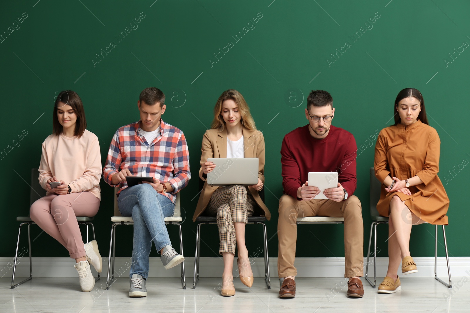 Photo of People waiting for job interview near green wall indoors