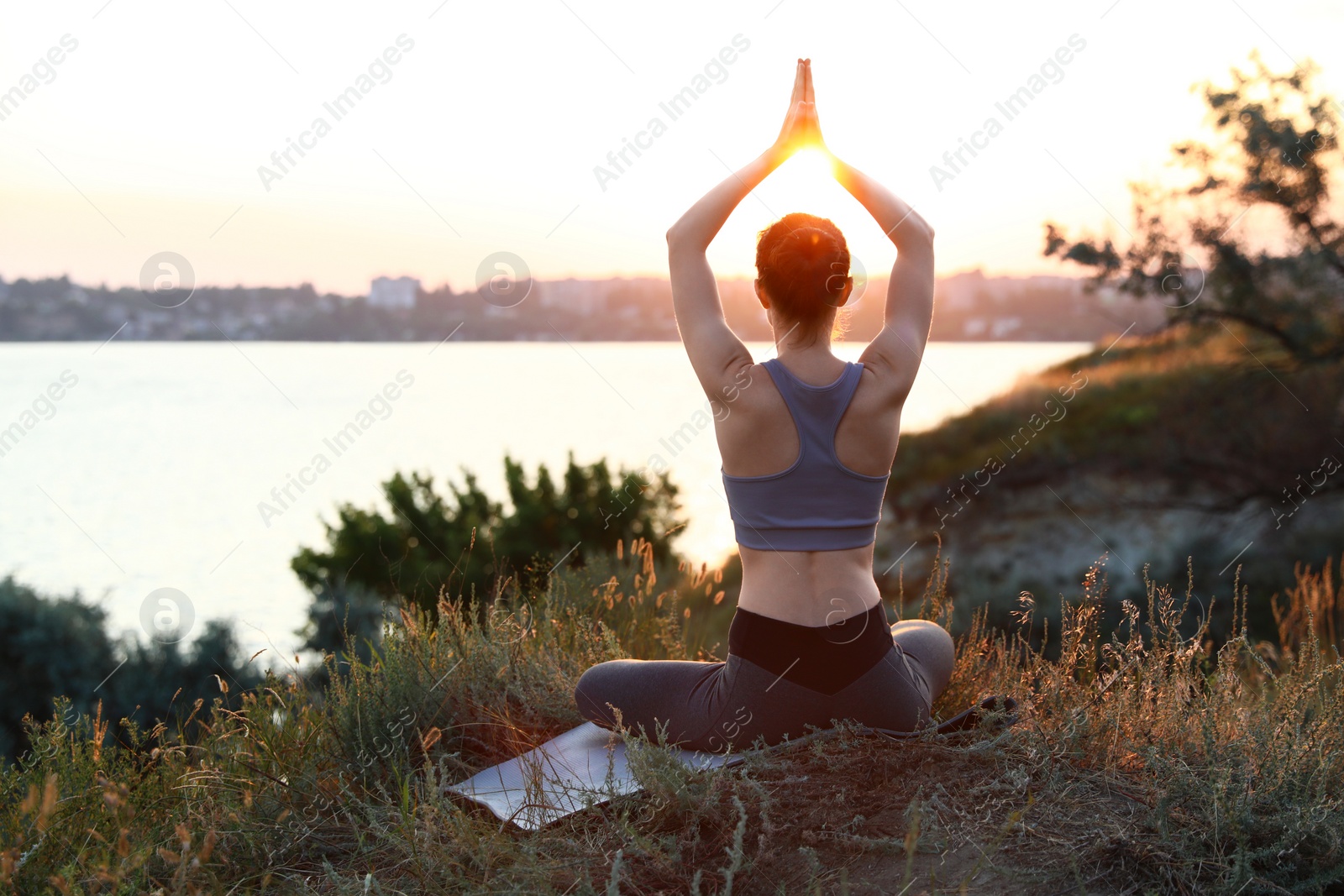 Photo of Young woman practicing yoga outdoors on sunset. Zen meditation