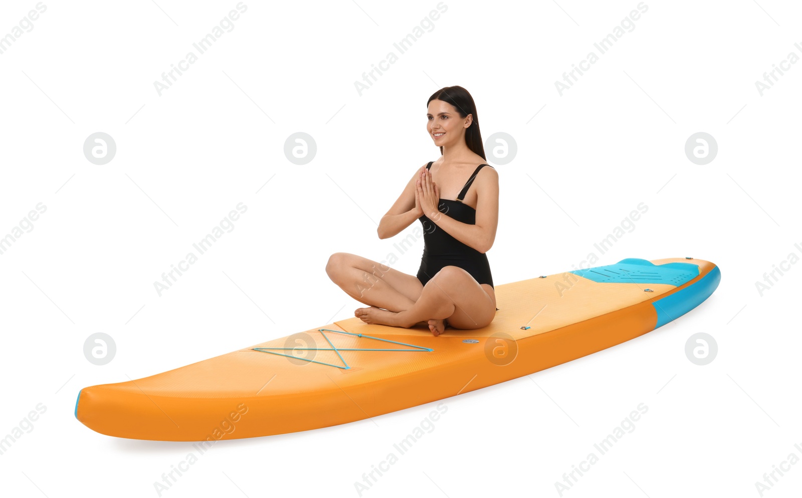 Photo of Happy woman practicing yoga on orange SUP board against white background