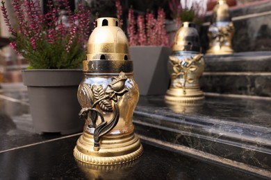 Photo of Golden grave lanterns on granite stairs at cemetery