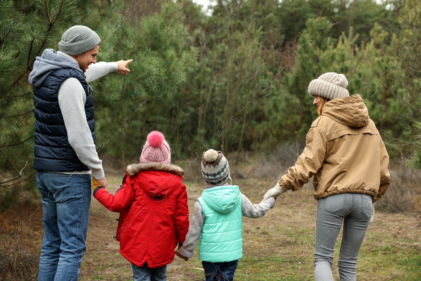 Photo of Happy family spending time together in forest, back view