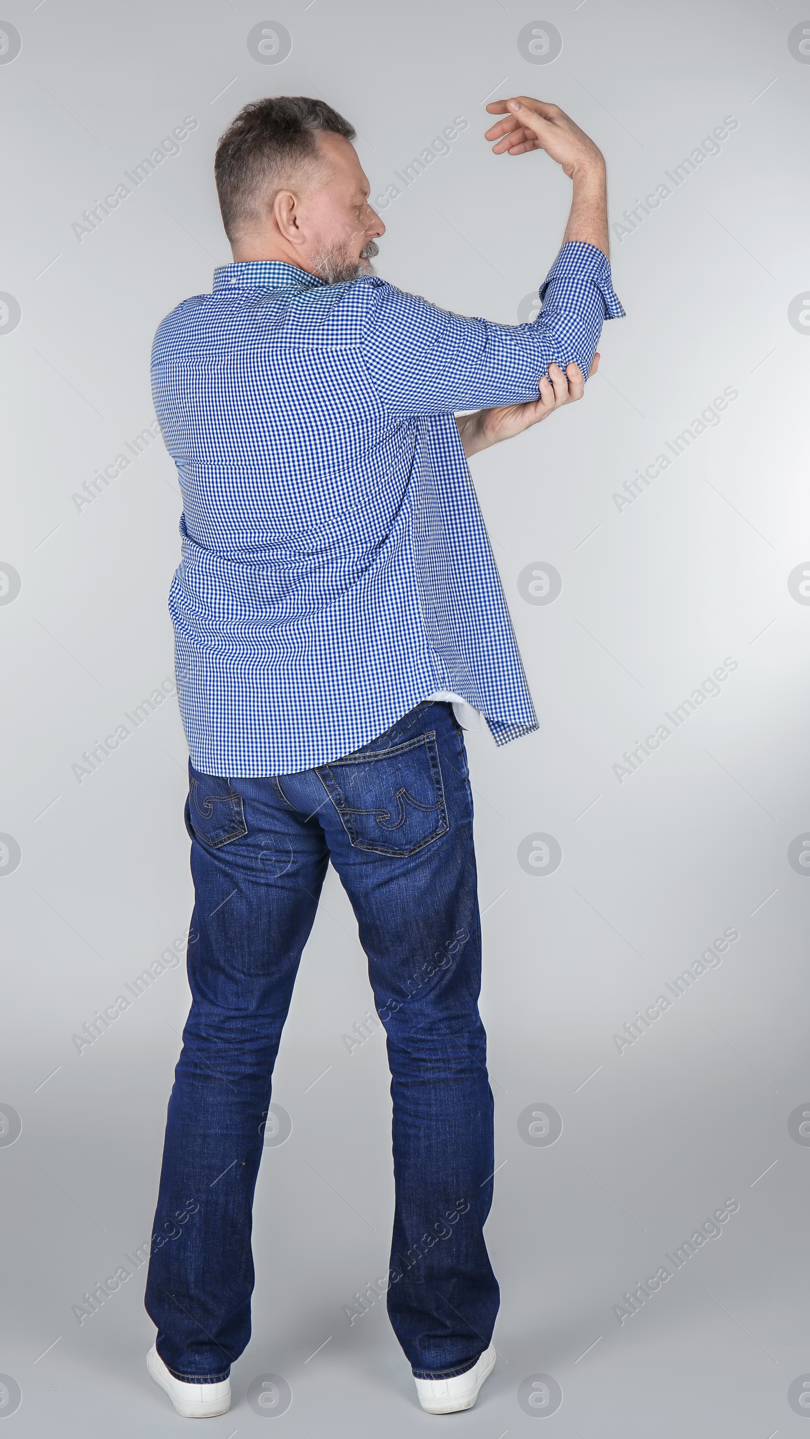 Photo of Man suffering from elbow pain on light background