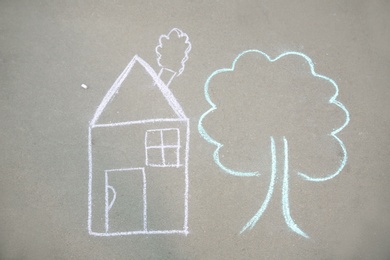 Child's chalk drawing of house and tree on asphalt, top view