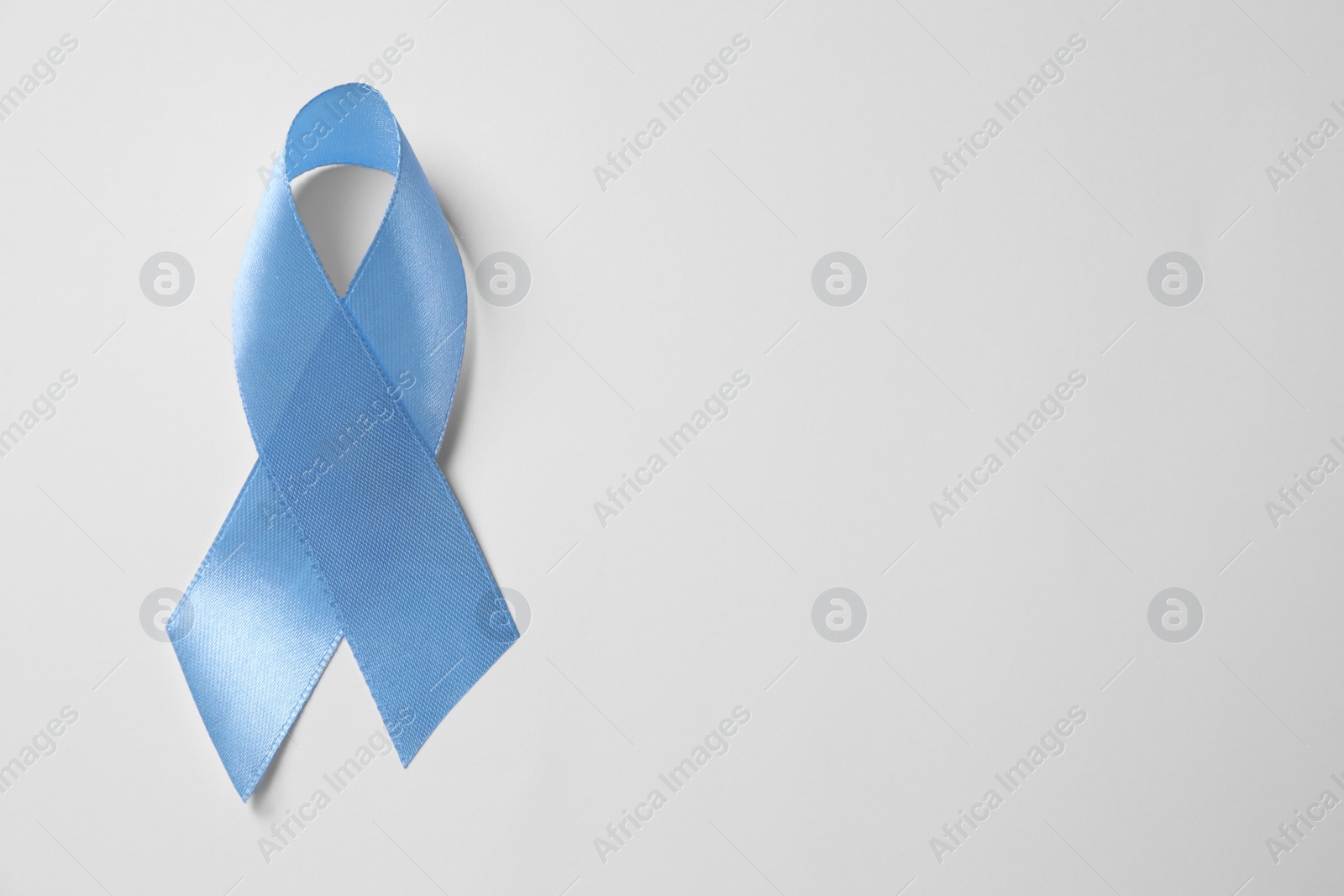 Photo of International Psoriasis Day. Light blue ribbon as symbol of support on white background, top view. Space for text