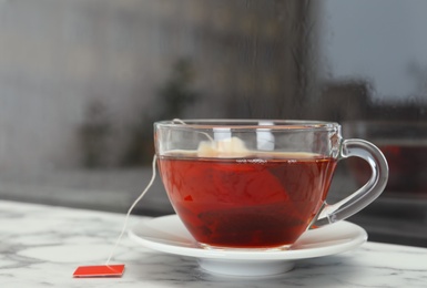 Photo of Glass cup of hot tea on window sill. Space for text