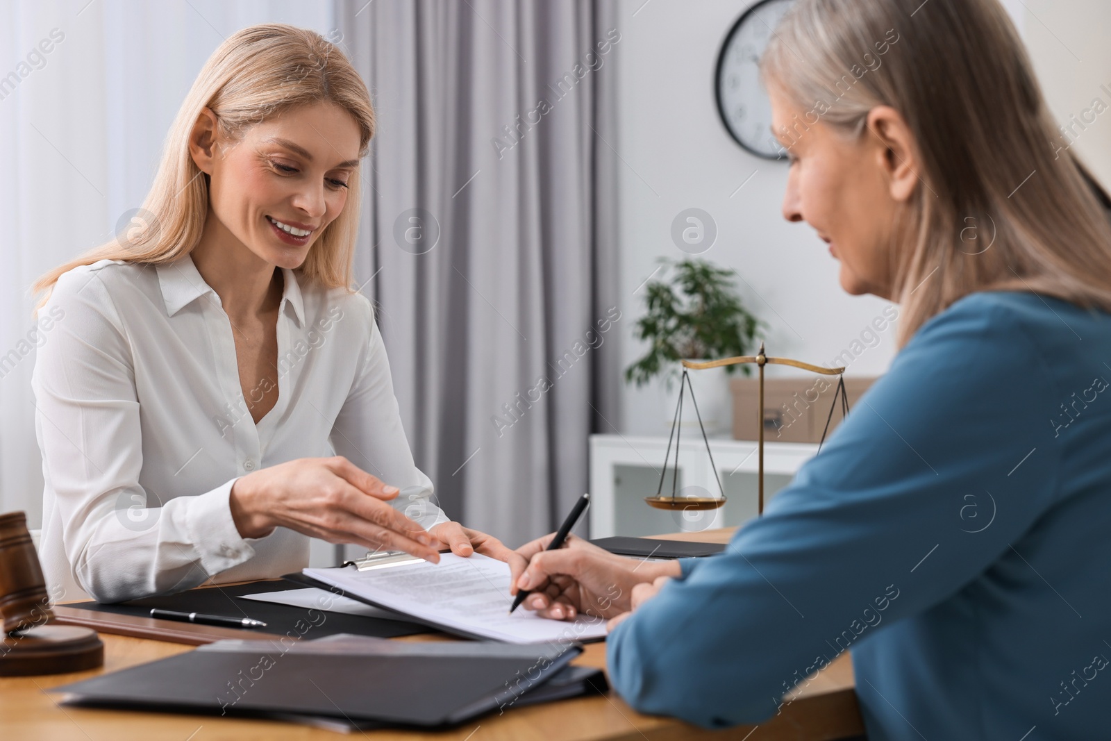 Photo of Senior woman signing document in lawyer's office