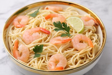 Tasty spaghetti with shrimps, lime and parsley in bowl on white table, closeup