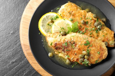 Photo of Delicious chicken piccata on black table, top view