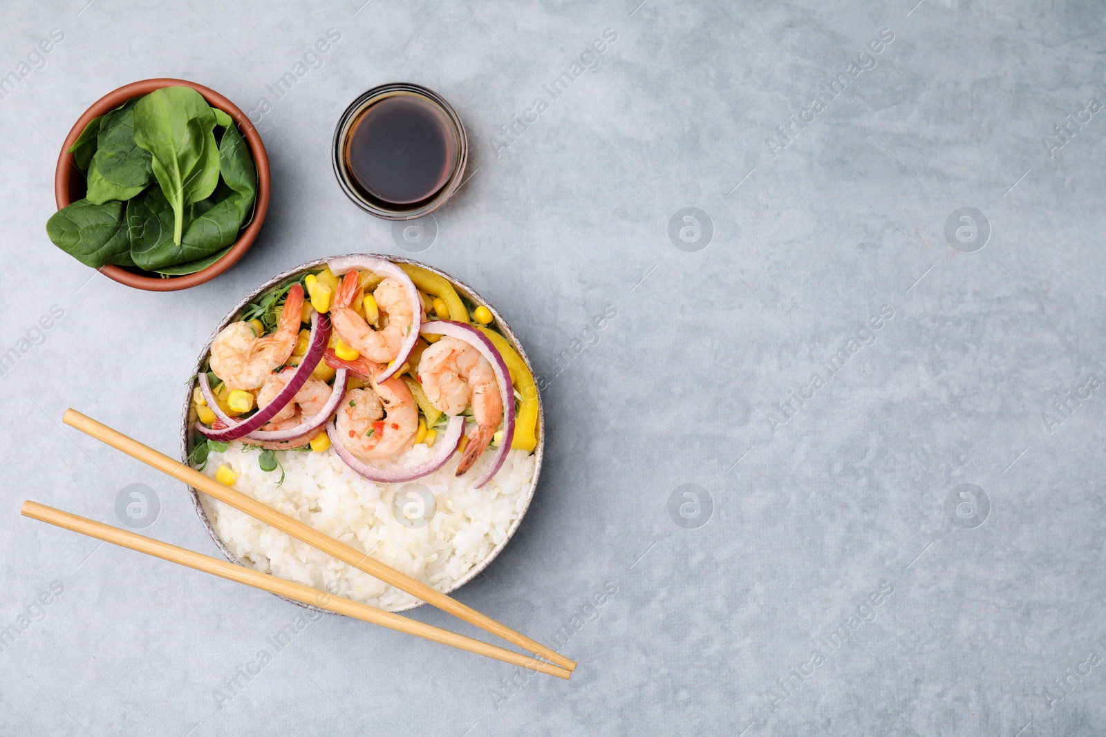 Photo of Delicious poke bowl with shrimps, rice and vegetables served on light grey table, flat lay. Space for text