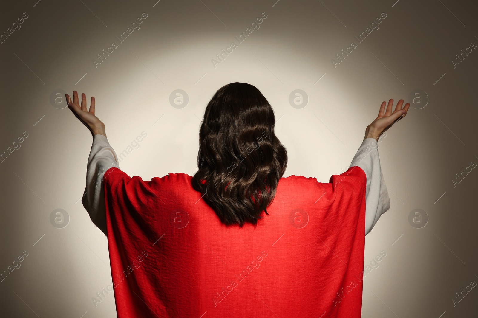 Photo of Jesus Christ with outstretched arms on beige background, back view