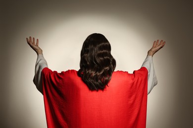 Photo of Jesus Christ with outstretched arms on beige background, back view
