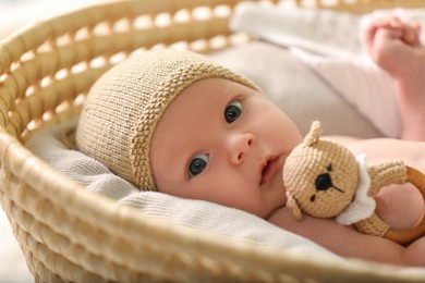 Photo of Cute newborn baby on white blanket in wicker crib, closeup