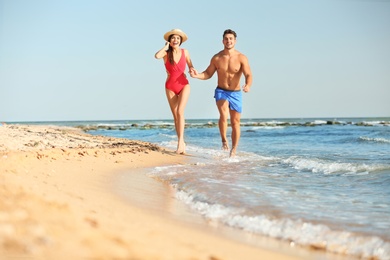 Happy young couple having fun at beach on sunny day