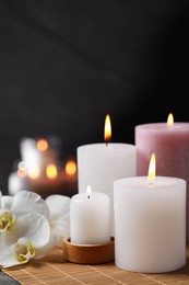 Photo of Burning candles and flowers against black background. Spa therapy