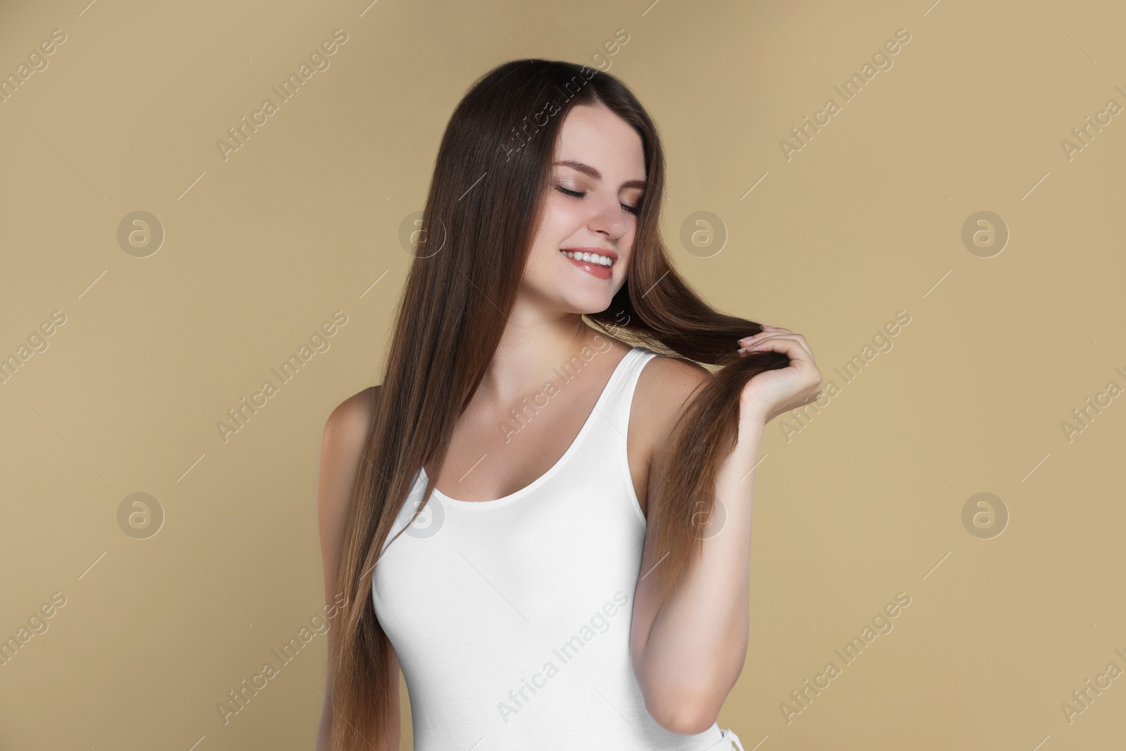 Photo of Young woman with strong healthy hair on beige background