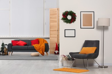 Photo of Comfortable furniture in stylish room decorated for Christmas. Interior design