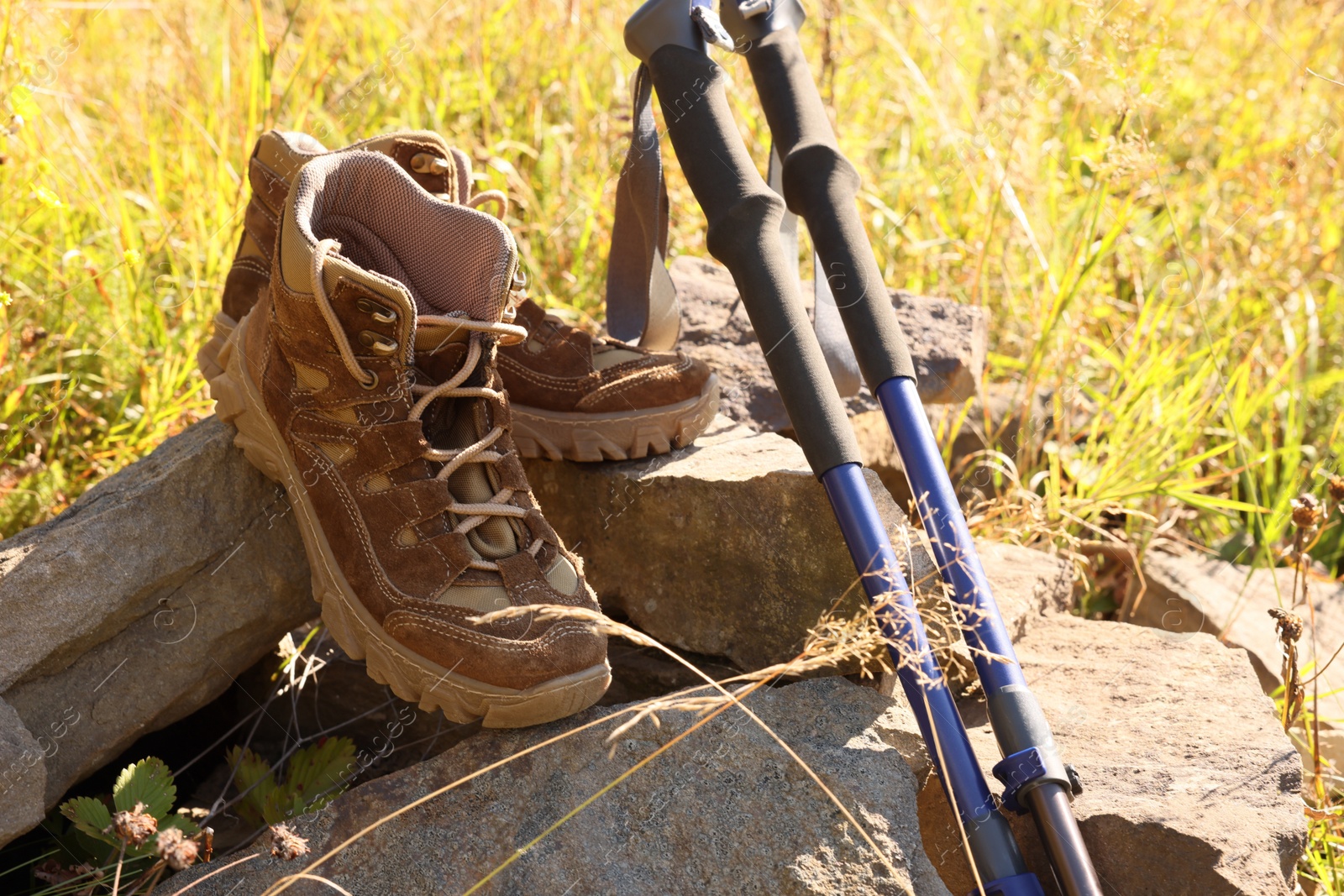 Photo of Trekking poles and hiking sneakers on pile of rocks in nature