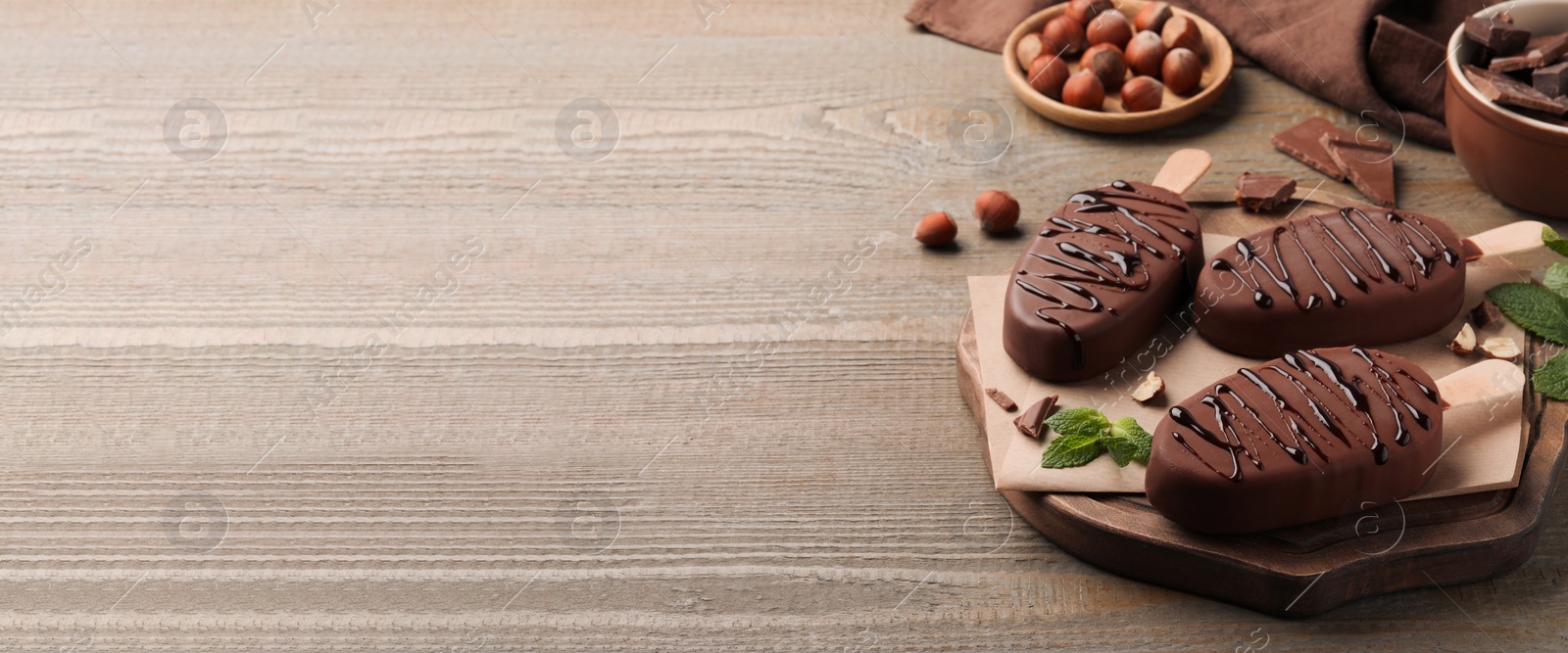 Image of Delicious glazed ice cream bars, nuts and mint on wooden table, space for text. Banner design