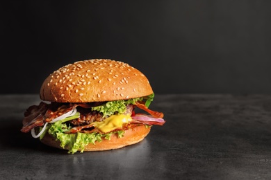 Photo of Tasty burger with bacon on dark background