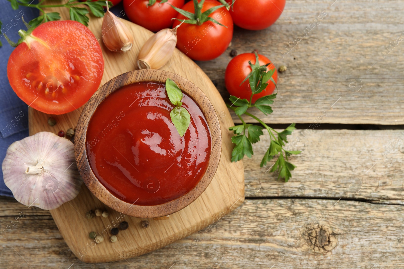 Photo of Tasty ketchup, fresh tomatoes, parsley and spices on wooden table, flat lay. Space for text