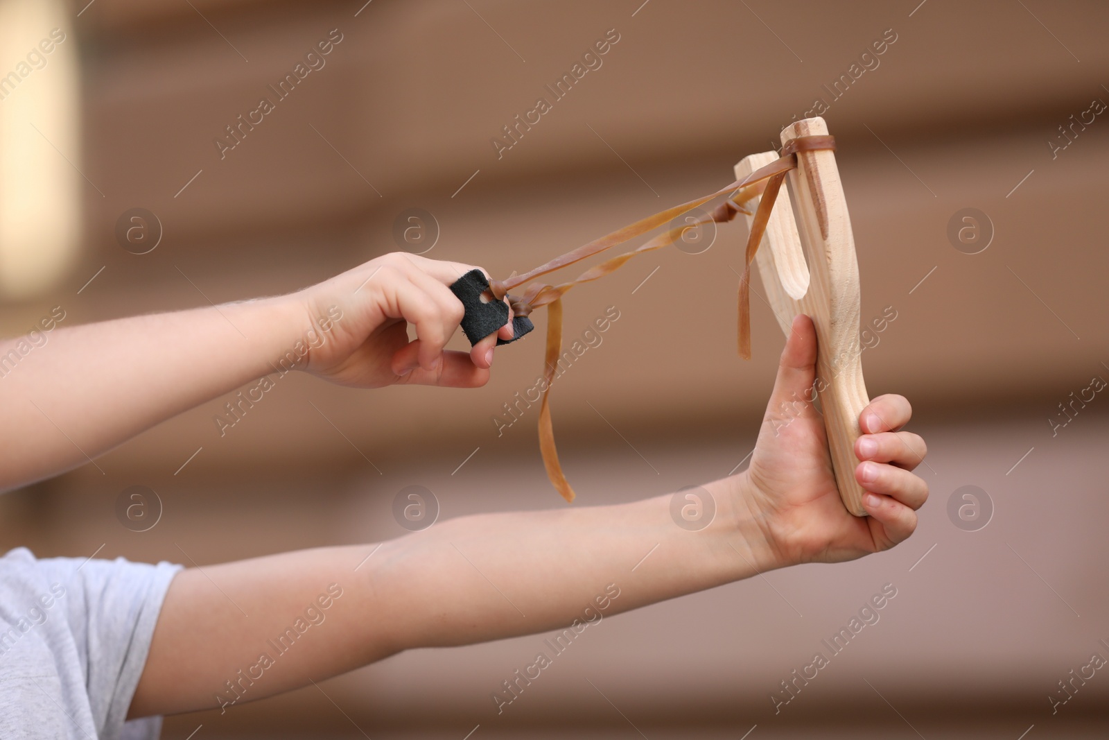 Photo of Little girl playing with slingshot outdoors, closeup