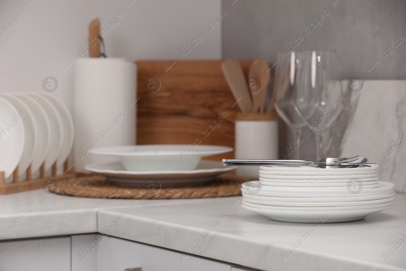 Photo of Clean dishes and cutlery on light countertop in kitchen