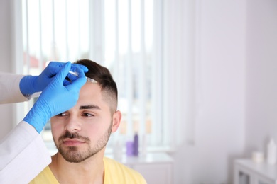 Photo of Young man with hair loss problem receiving injection in salon