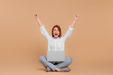 Photo of Happy young woman with laptop on beige background