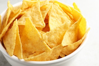 Photo of Bowl with tasty tortilla chips (nachos) on grey table, closeup