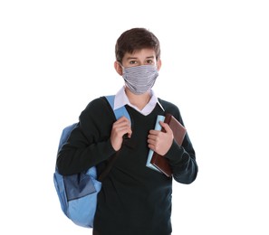 Boy wearing protective mask with backpack and books on white background. Child safety